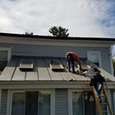 workers installing double lock standing seam metal roofing around sky lights