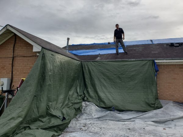 hanging tarps to protect property on roof replacement job